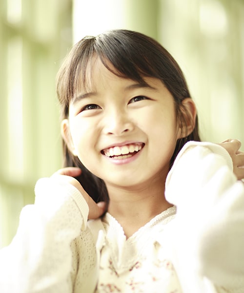 A girl smiling while touching her hair