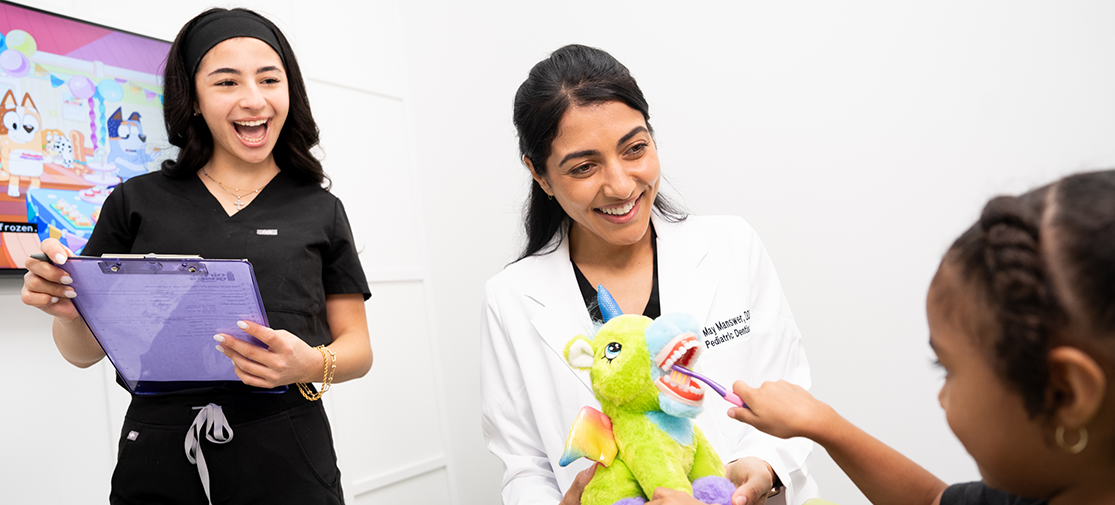 Dr. May Manswer and dental assistant in las vegas dental office with a little girl sitting and smiling in the dentist's chair